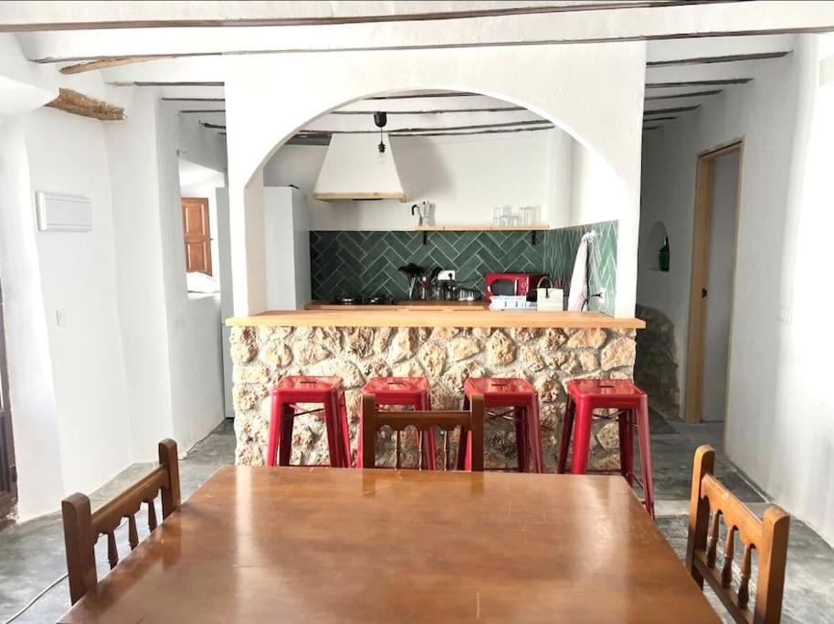 a dining room with a table and red stools at Casas de Vela in Vélez Blanco