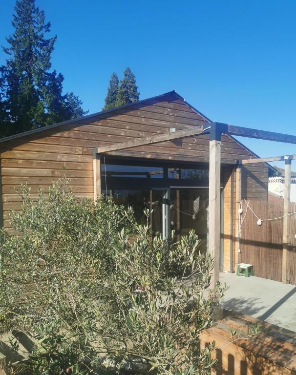 un bâtiment en bois avec une clôture devant lui dans l'établissement Gîte de plain-pied, à Les Abrets en Dauphine