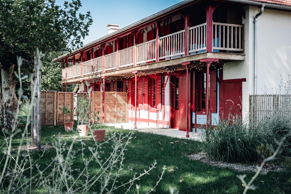 une maison rouge avec un balcon latéral dans l'établissement Maison Bleue Est 12 personnes, à Saint-Julien-en-Born
