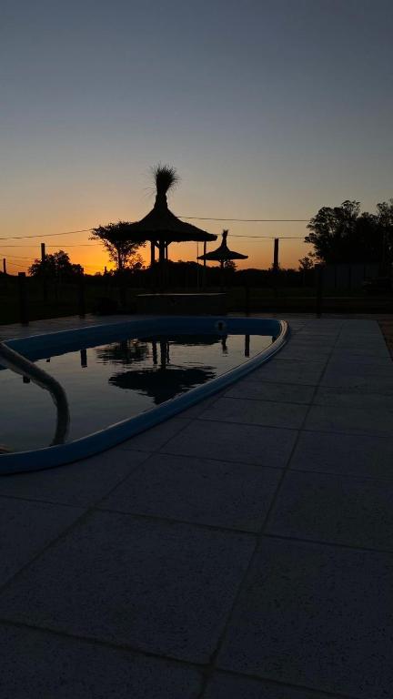 a large pool with a sunset in the background at La Vita CdelU in Concepción del Uruguay