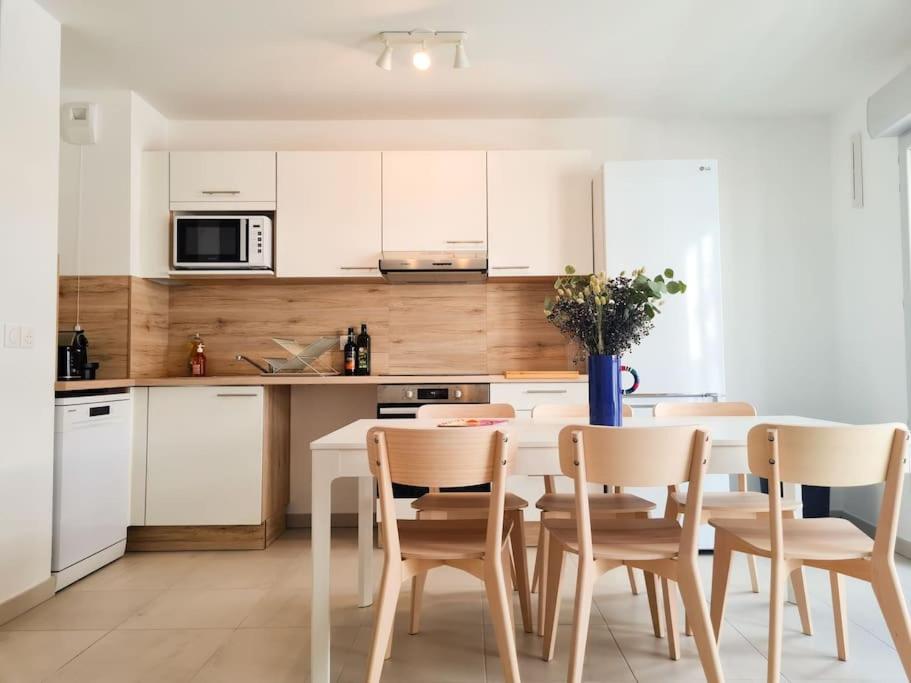 une cuisine avec des armoires blanches et une table et des chaises dans l'établissement Magnifique Appartement - Parking privé - Nice, à Nice