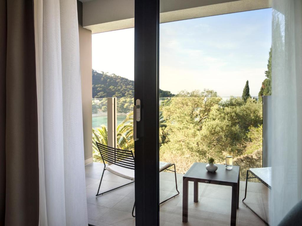 a room with a glass door with a chair and a table at Hotel Kompas in Dubrovnik
