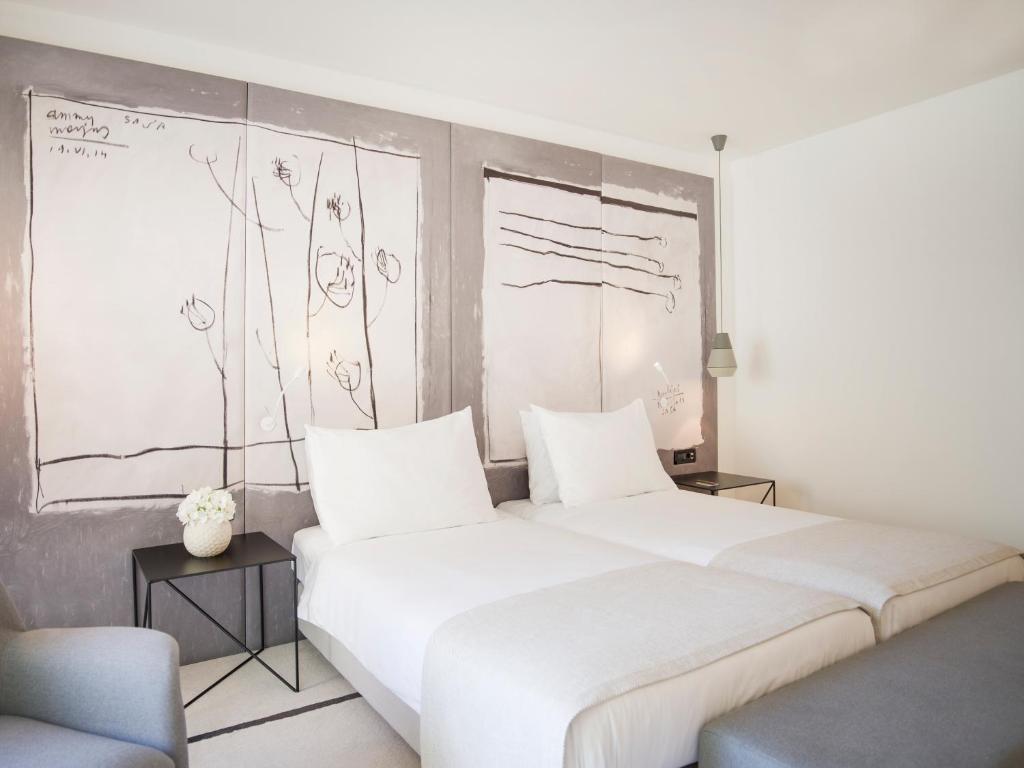 a bedroom with a large white bed and drawings on the wall at Hotel Kompas in Dubrovnik
