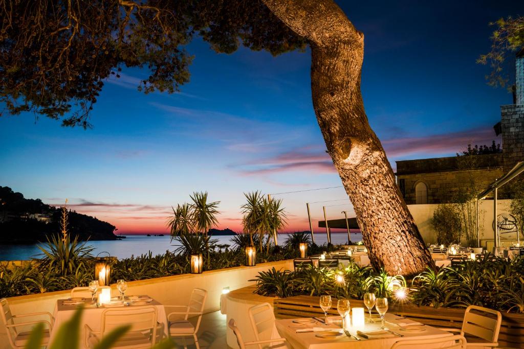 a restaurant with tables and chairs and a tree at Hotel Kompas in Dubrovnik