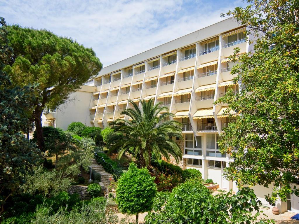 un immeuble d'appartements avec des arbres devant lui dans l'établissement Hotel Kimen, à Cres