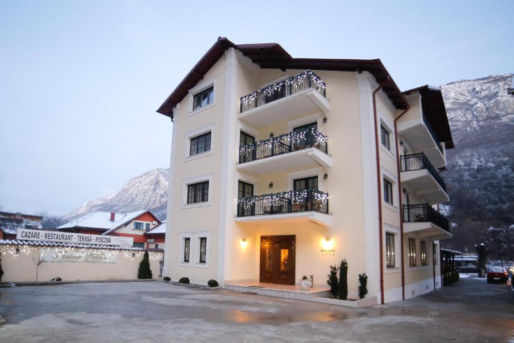 a large white building with balconies and a parking lot at Pension Noblesse in Băile Herculane