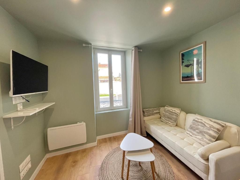 un salon avec un canapé et une télévision dans l'établissement Le Numéro 2, à Saint-Jean-dʼAngély