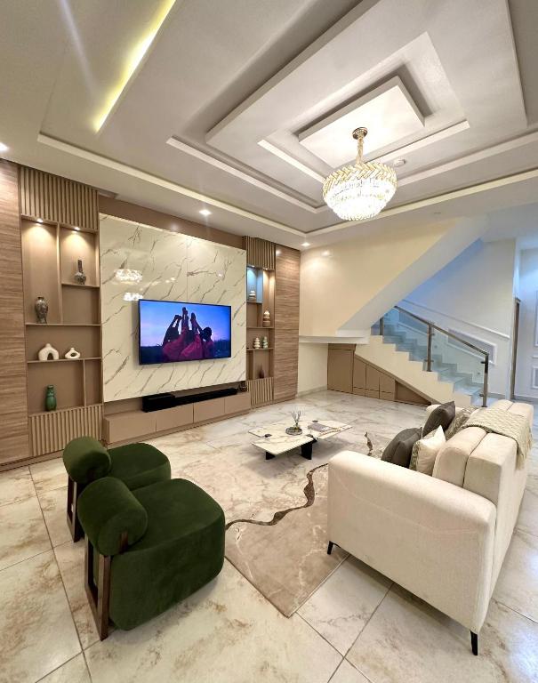 a living room with a couch and a tv at EliteunseenSuites - 5 Bedroom Beautiful Detached House - Private Parking in Lekki