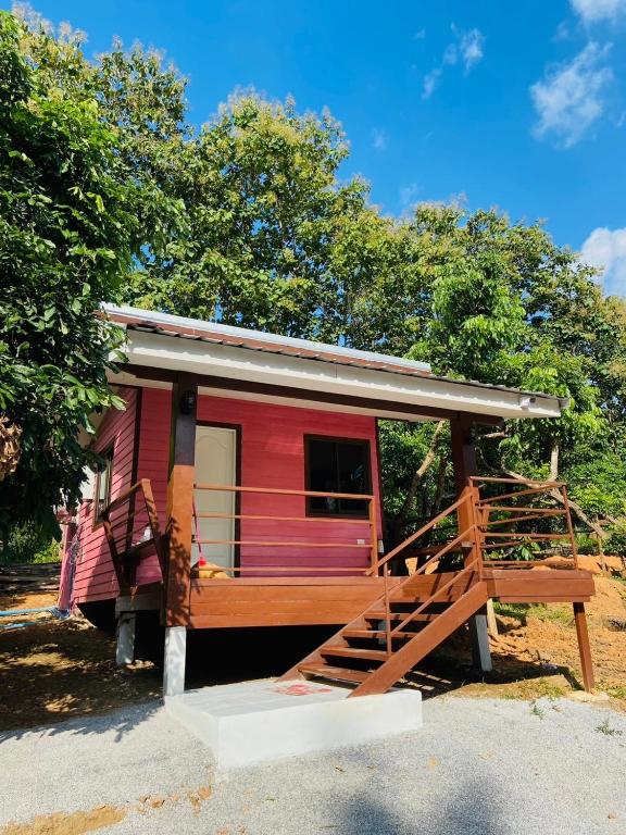 a red tiny house with a wooden porch at ตาแอกะยายแดงโฮมสเตย์ in Ban Hong Khu