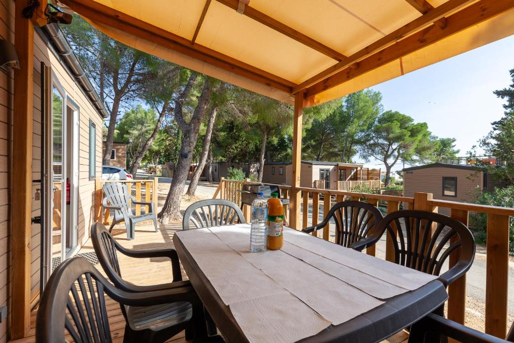 une table et des chaises en bois sur une terrasse dans l'établissement MOBIL HOME Neuf FRONT DE MER TOUT CONFORT 5 LITS 6 personnes CARRY LE ROUET, à Carry-le-Rouet