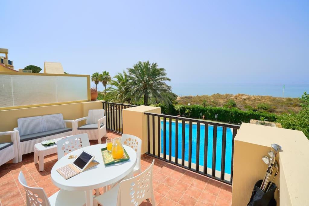 a balcony with a table and chairs and a pool at OleHolidays 821 Romana Playa frente al mar in Marbella