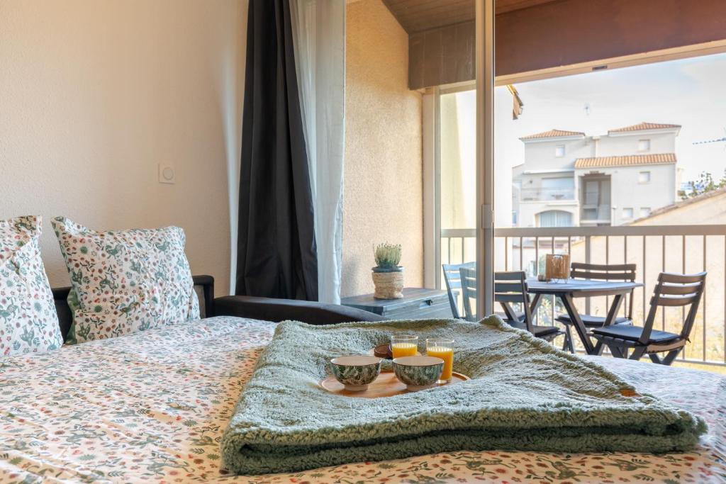 La plage Wifi Climatisation Terrasse Parking Proche mer et commerces في فالراس بلاج: سرير عليه صينية طعام ومشروبات