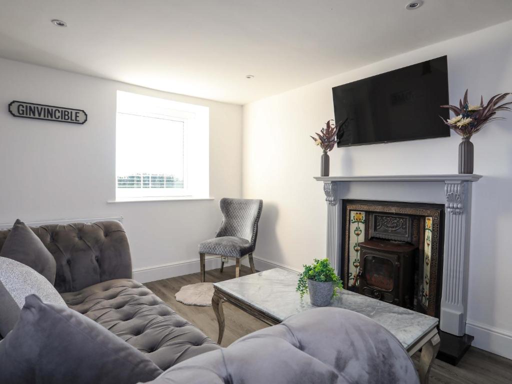 a living room with a couch and a fireplace at Ty'n Ffridd in Pwllheli