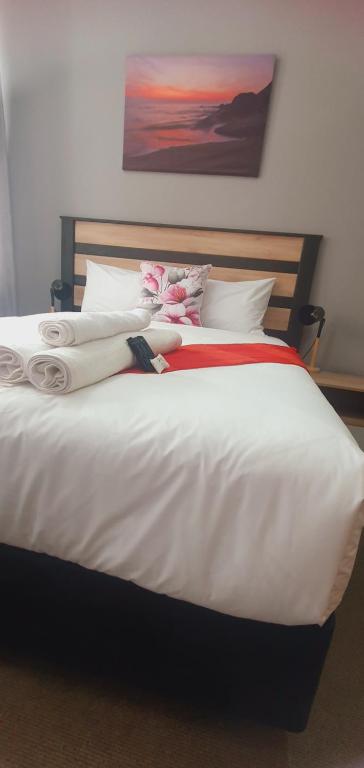 a large white bed with white sheets and red blanket at Isibaya House in Johannesburg
