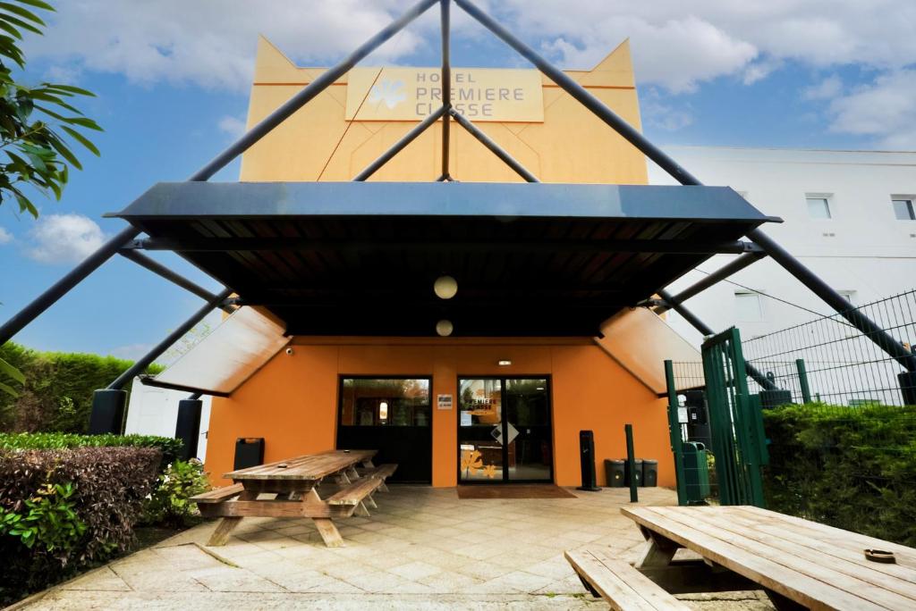 a building with two picnic tables in front of it at Première Classe Plaisir Gatines in Plaisir