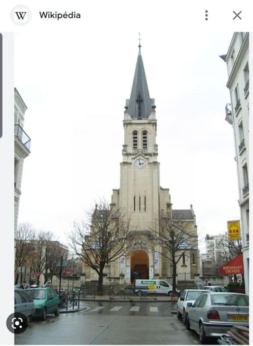 une église avec une tour d'horloge dans une ville dans l'établissement Charmant nid au cœur de Paris, à Paris