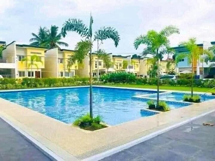 a large swimming pool with palm trees in front of a building at Diamond Heights A near Davao Airport in Davao City