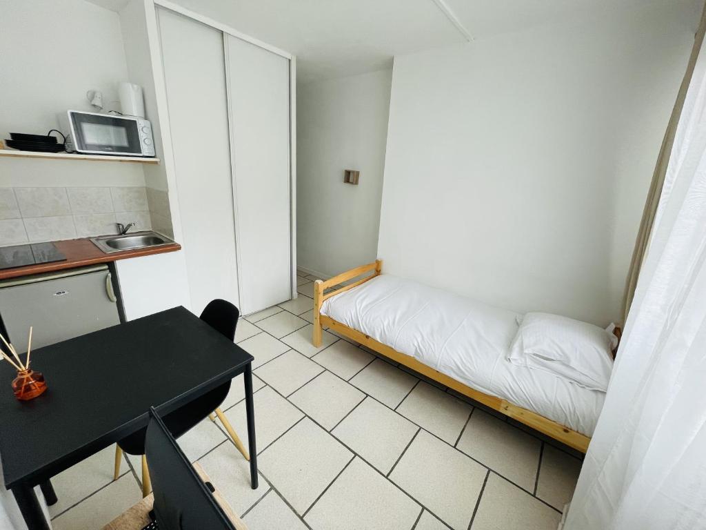 une petite pièce avec un lit et une table dans l'établissement Banyo, Studio 1p proche centre ville, à Caen