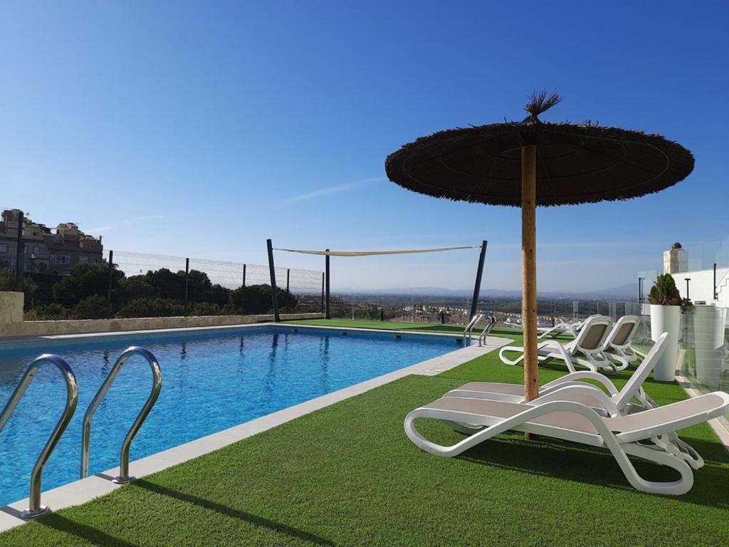 une piscine avec des chaises et un parasol dans l'établissement Precioso apartamento con piscina y jacuzzi R100 by Novadesta, à Puerto Marino