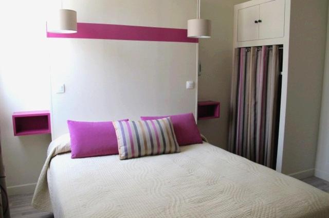a bed with a purple pillow on top of it at Hotel Le Havre Bleu in Beaulieu-sur-Mer