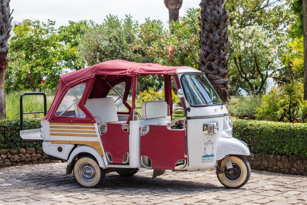 a red and white golf cart parked in a park at Villa Irlanda Grand Hotel in Gaeta