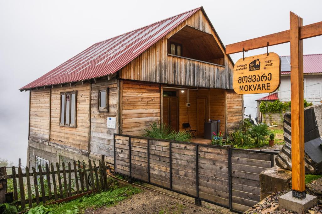 a small wooden house with a sign on a fence at Guest House Mokvare in Gundauri