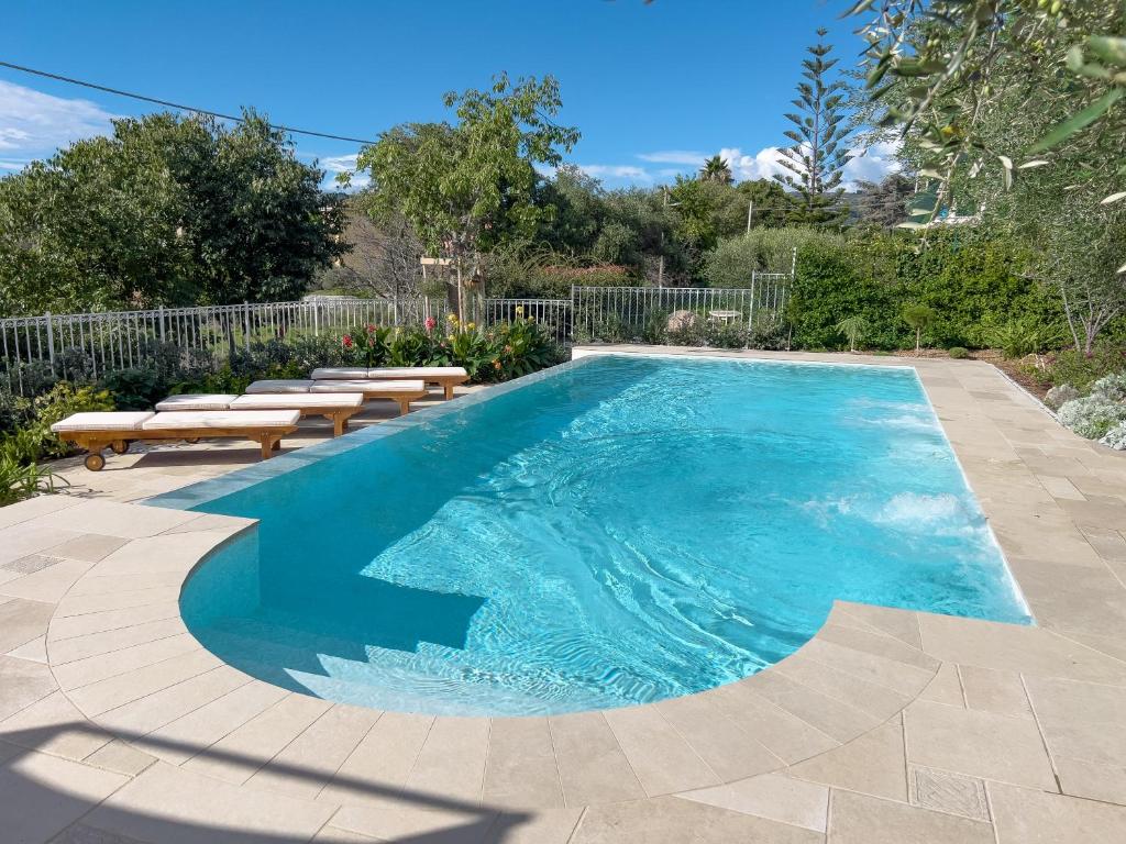 una piscina con dos bancos al lado en Villa La Rodina, en Diano Marina