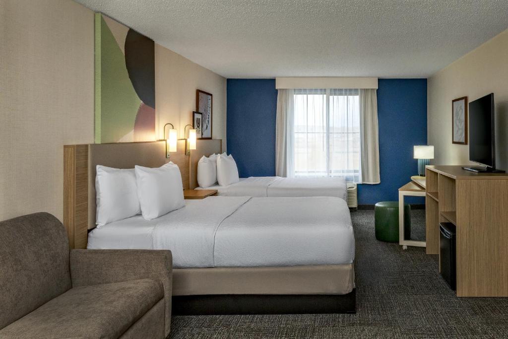a hotel room with two beds and a couch at Spark by Hilton Denver International Airport in Denver