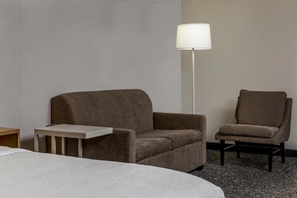 a room with a chair and a couch and a lamp at Spark by Hilton Denver International Airport in Denver
