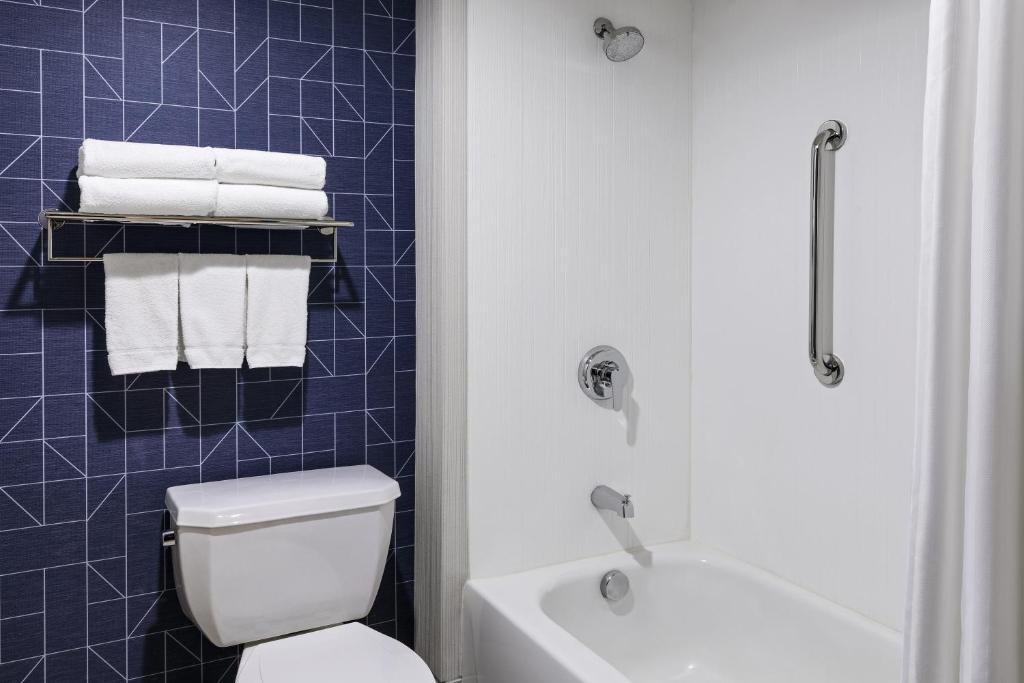 a bathroom with a white toilet and a blue tiled wall at Spark by Hilton Denver International Airport in Denver