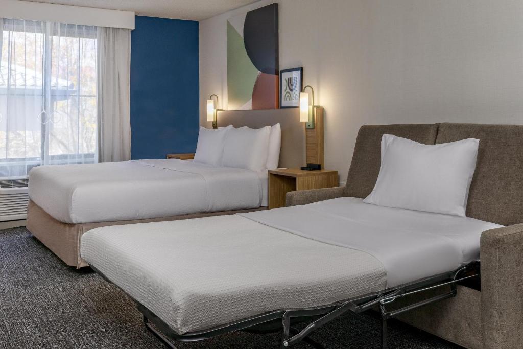 a hotel room with two beds and a chair at Spark by Hilton Denver International Airport in Denver