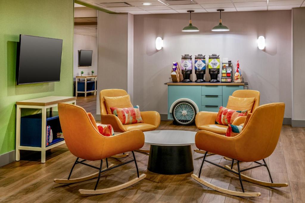 a waiting room with chairs and a table and a tv at Spark by Hilton Denver International Airport in Denver