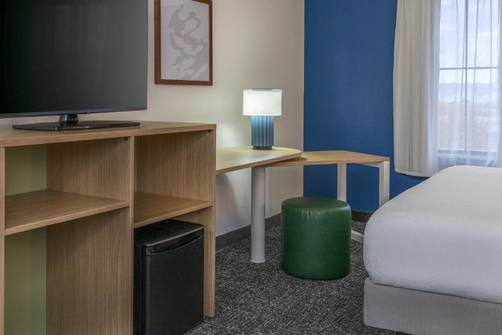 a room with a bed and a desk with a television at Spark by Hilton Denver International Airport in Denver