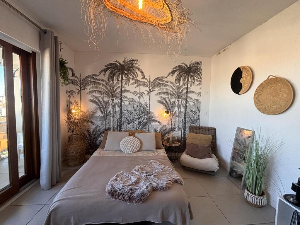 a bedroom with a bed and palm trees on the wall at Studio calme -304- in Canet-en-Roussillon