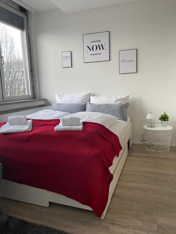Un dormitorio con una cama grande con una manta roja. en Modernes City-Apartment Nähe Uniklinikum und Zentrum, en Augsburg