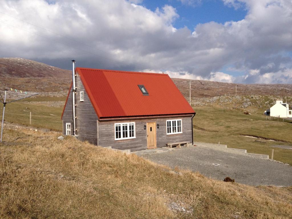 a small house with an orange roof on a hill at Harris Cuckoo Cottage in Luskentyre