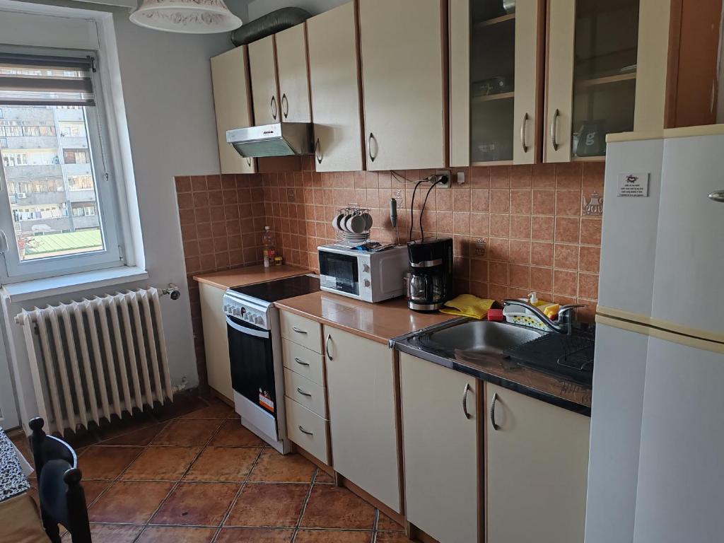 Una cocina con gabinetes blancos, un fregadero y un microondas. en Relax apartman bg, en Belgrado