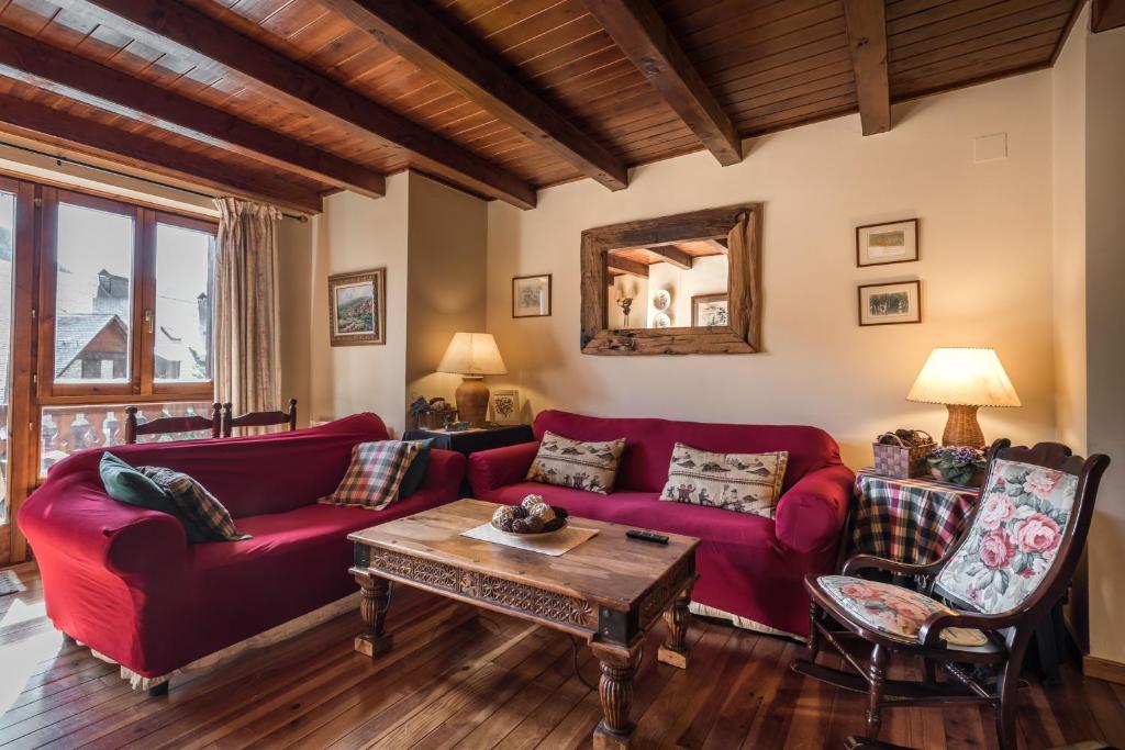 a living room with a red couch and a table at Roca Blanca by Totiaran in Naut Aran