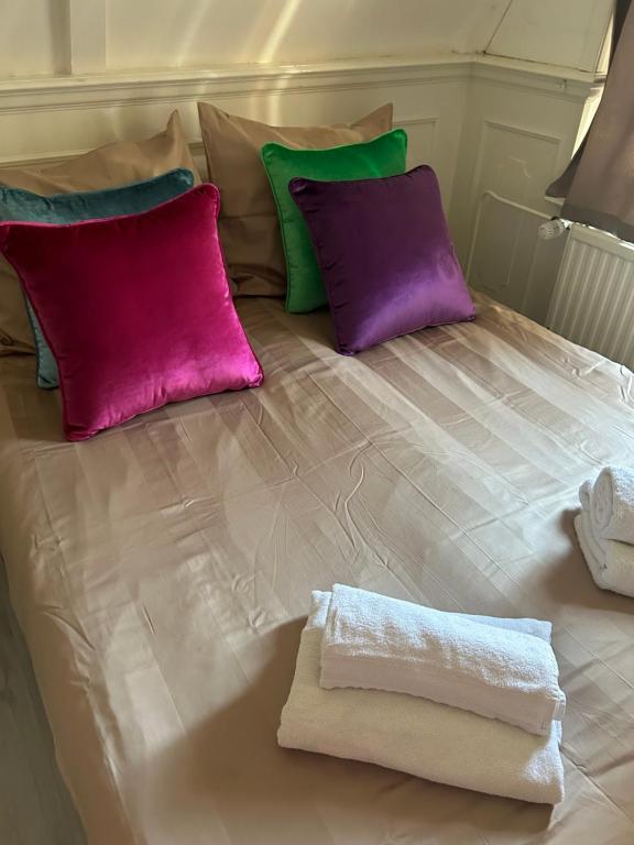 a bed with purple and green pillows and a towel at Cosy by Mandy in Amsterdam