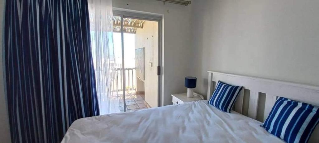 Un dormitorio con una cama con almohadas azules y blancas. en The Sunset Catcher - Langebaan, en Langebaan