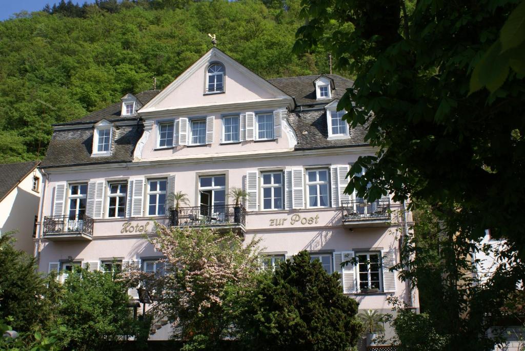 ein großes weißes Haus mit weißen Fenstern und Bäumen in der Unterkunft Romantisches Hotel zur Post in Brodenbach