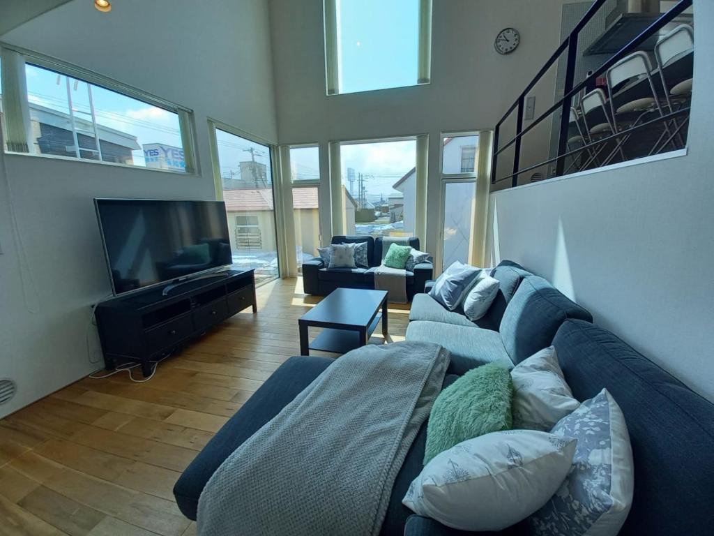 ein Wohnzimmer mit einer blauen Couch und einem Flachbildfernseher in der Unterkunft Echo Lodge in Kutchan