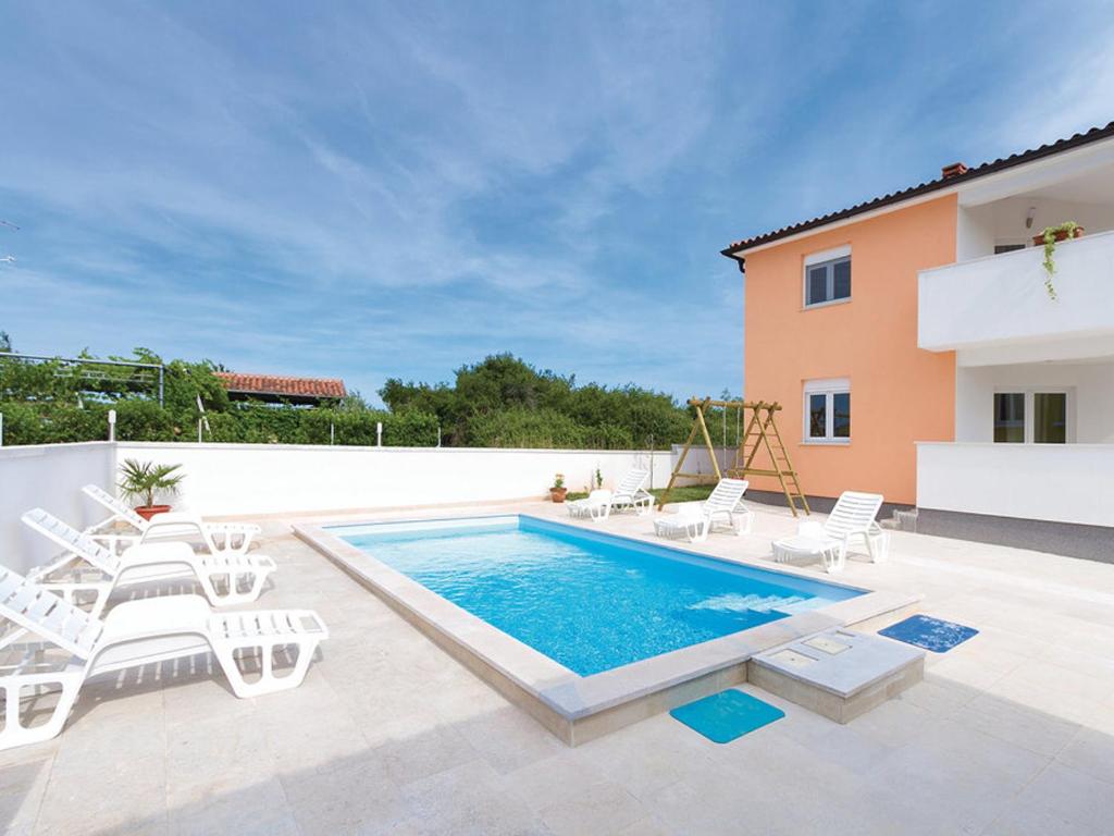 a swimming pool with white chairs and a house at Villa Patricia in Štinjan