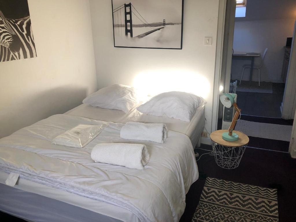 un lit avec des draps blancs et des oreillers dans une chambre dans l'établissement Le Victor Hugo 4 D et sa pizza offerte, à Aurillac