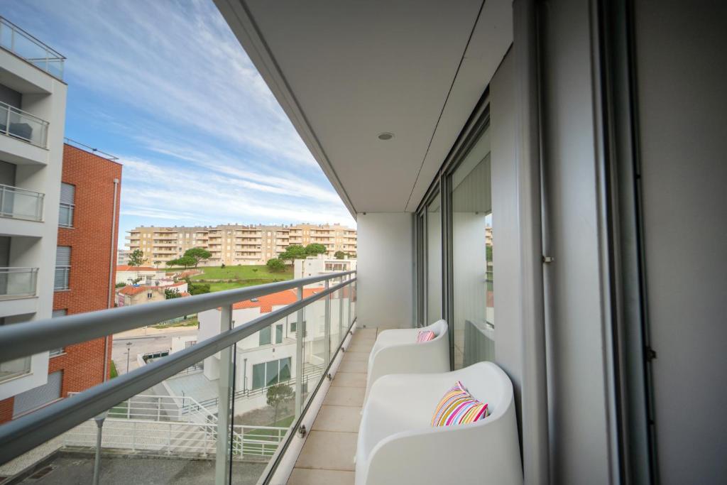 a balcony with white chairs and a view of a city at Apartamento Lux 1882 in Figueira da Foz