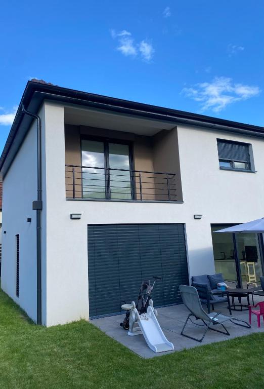 une maison blanche avec une porte de garage et une pelouse dans l'établissement Maison proche marché de Noel, à Wintzenheim