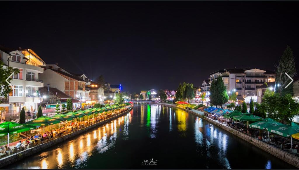 a river with buildings and a city at night at Hotel Palace Struga in Struga