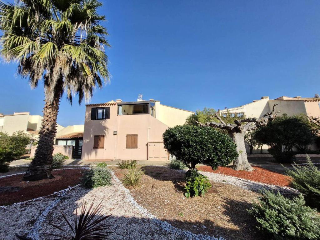 une maison avec un palmier devant dans l'établissement Résidence Helios - APPT T2 CAB OU MEZZ 5 couchages PORT LEUCATE MAE-1851, à Leucate