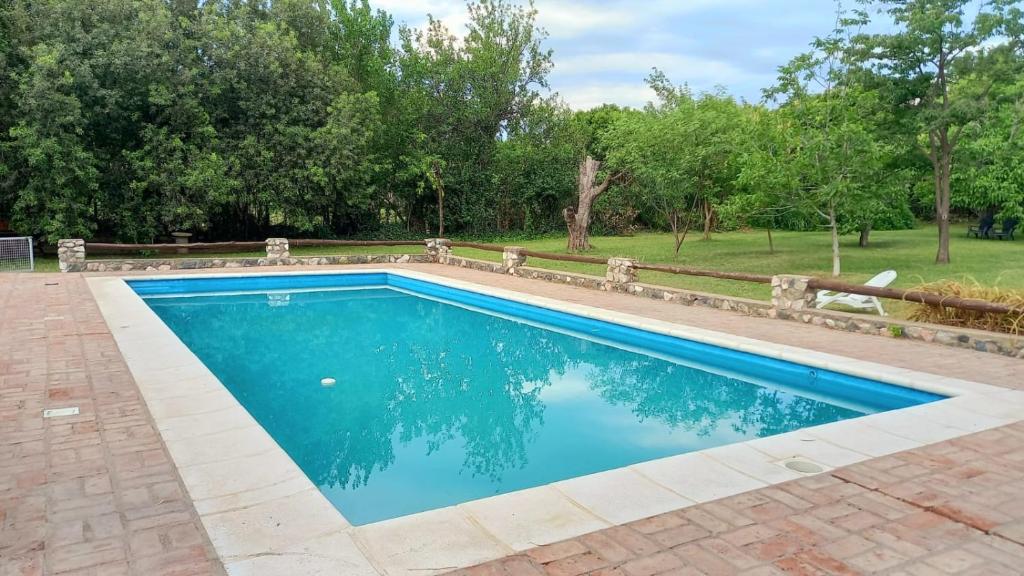 a swimming pool with blue water in a yard at Hostería Villa Luz Habitación 1 in San Marcos Sierras