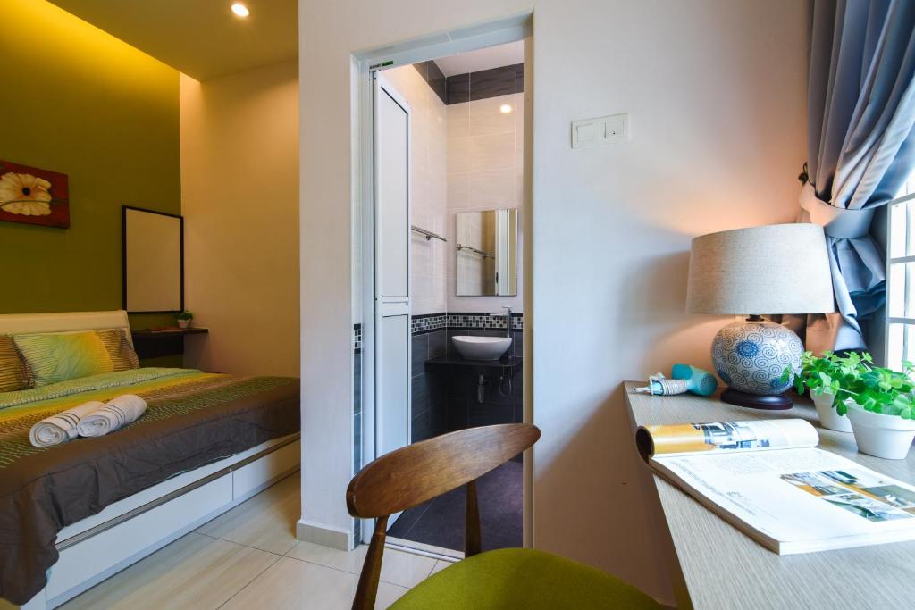 a small room with a bed and a desk with a lamp at Saffron Stay Melaka in Melaka
